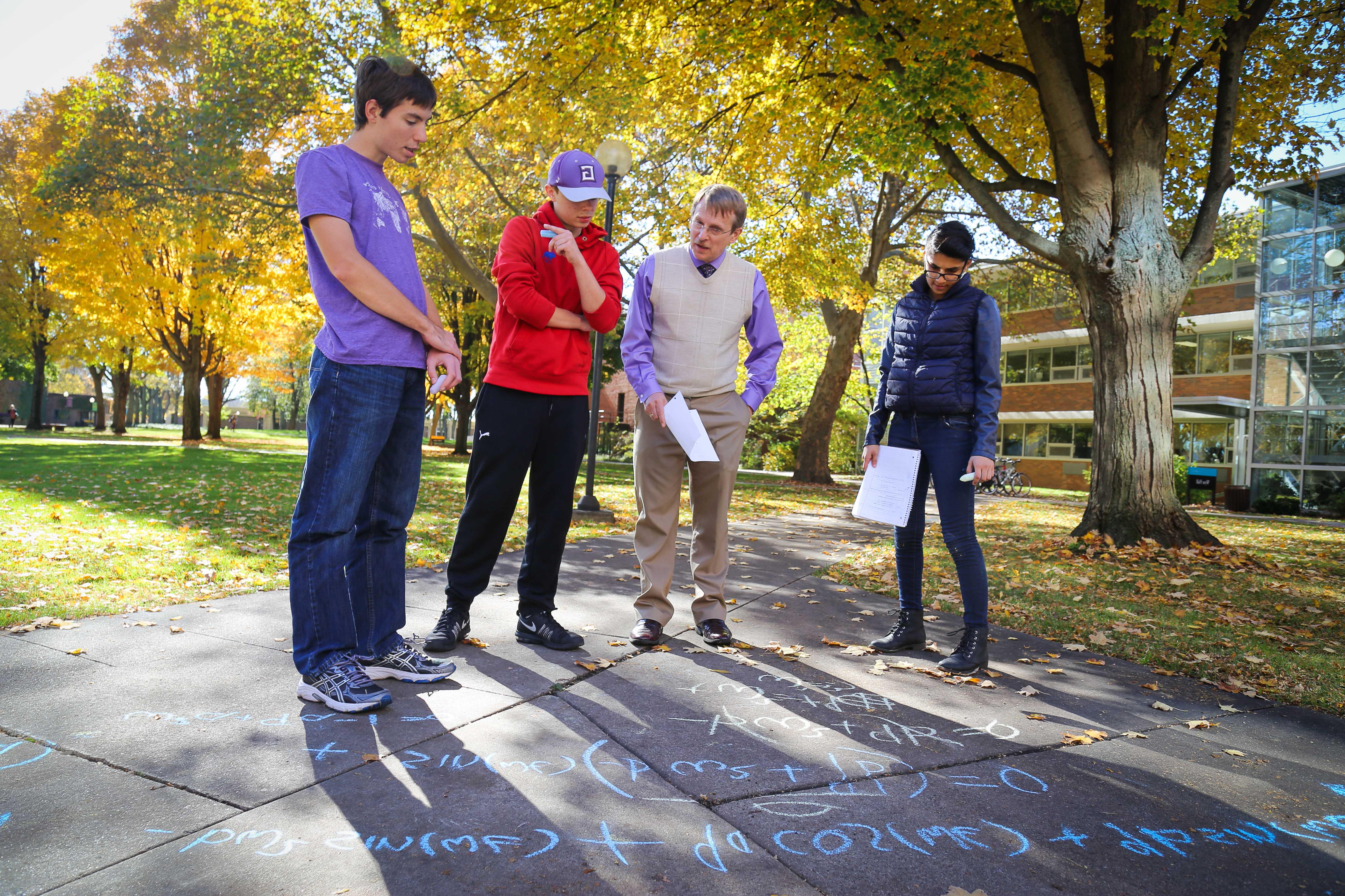 Math students with professor looking at equations on sidewalks